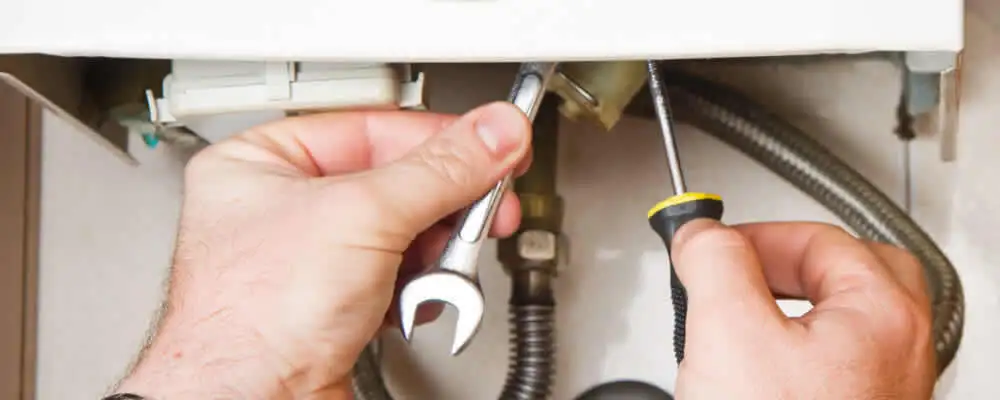 Boiler repair technician tightening pipe fittings and connections in Mesa, AZ