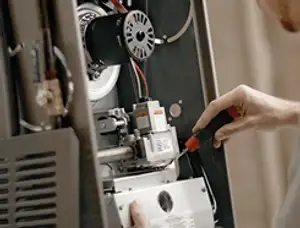 Furnace repair technician inspecting internal components and wiring in Mesa, AZ