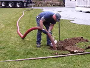 Septic pumping technician servicing a residential septic tank with a vacuum hose in Mesa, AZ