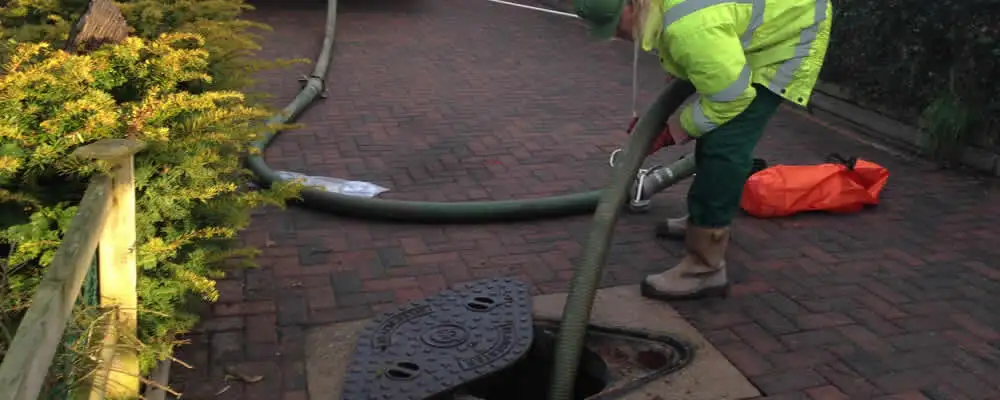 Septic tank cleaning technician servicing a septic tank with a vacuum hose in Mesa, AZ