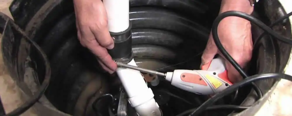Sump pump installation technician connecting PVC discharge piping in Mesa, AZ