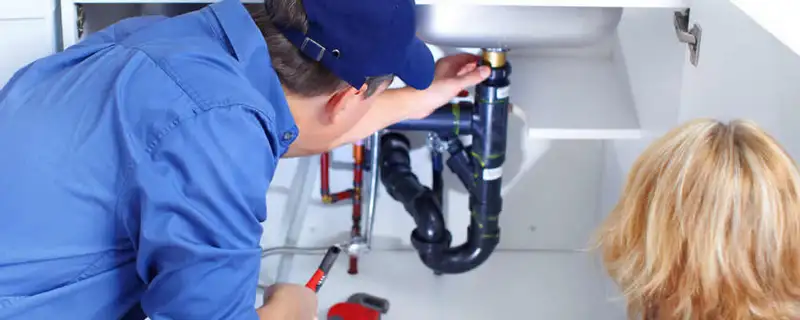 Plumber repairing under-sink drain pipes and fittings in Mesa, AZ